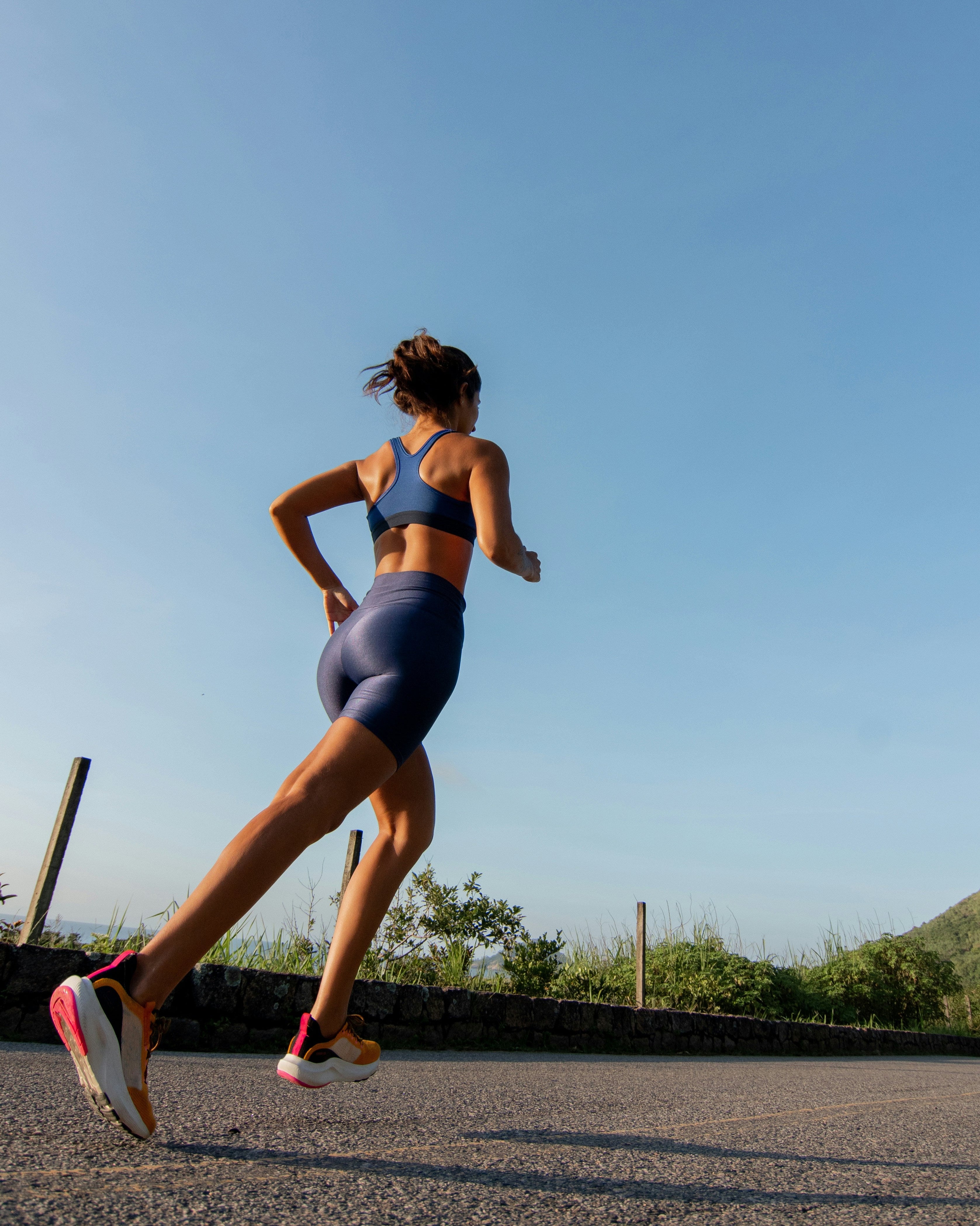 Woman running on a road with a clear blue sky
